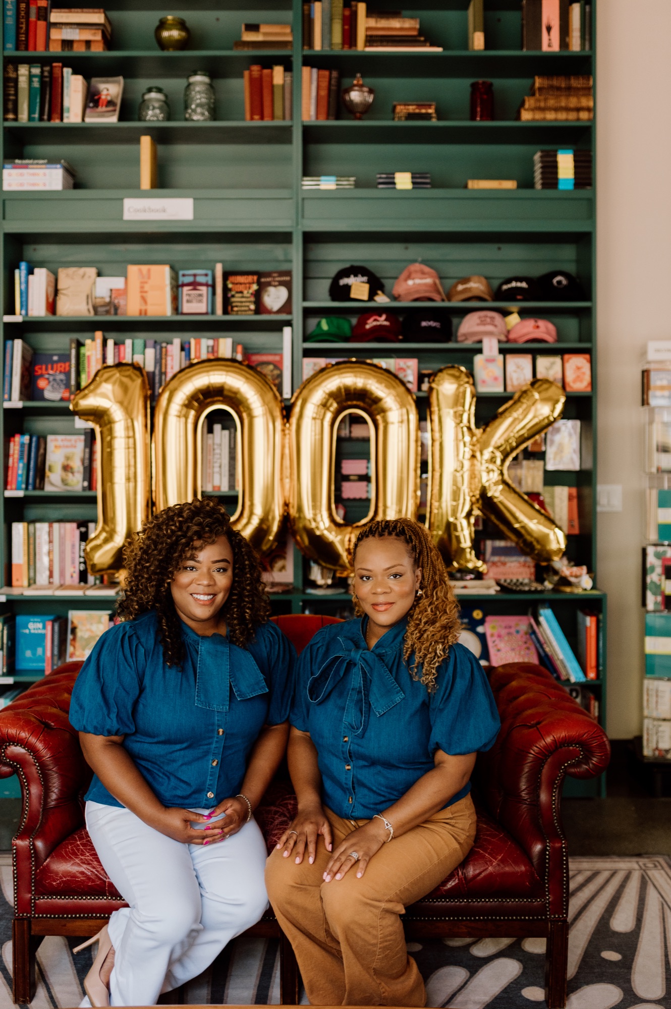 Tee and Tam seated together in front of their 100K celebration display