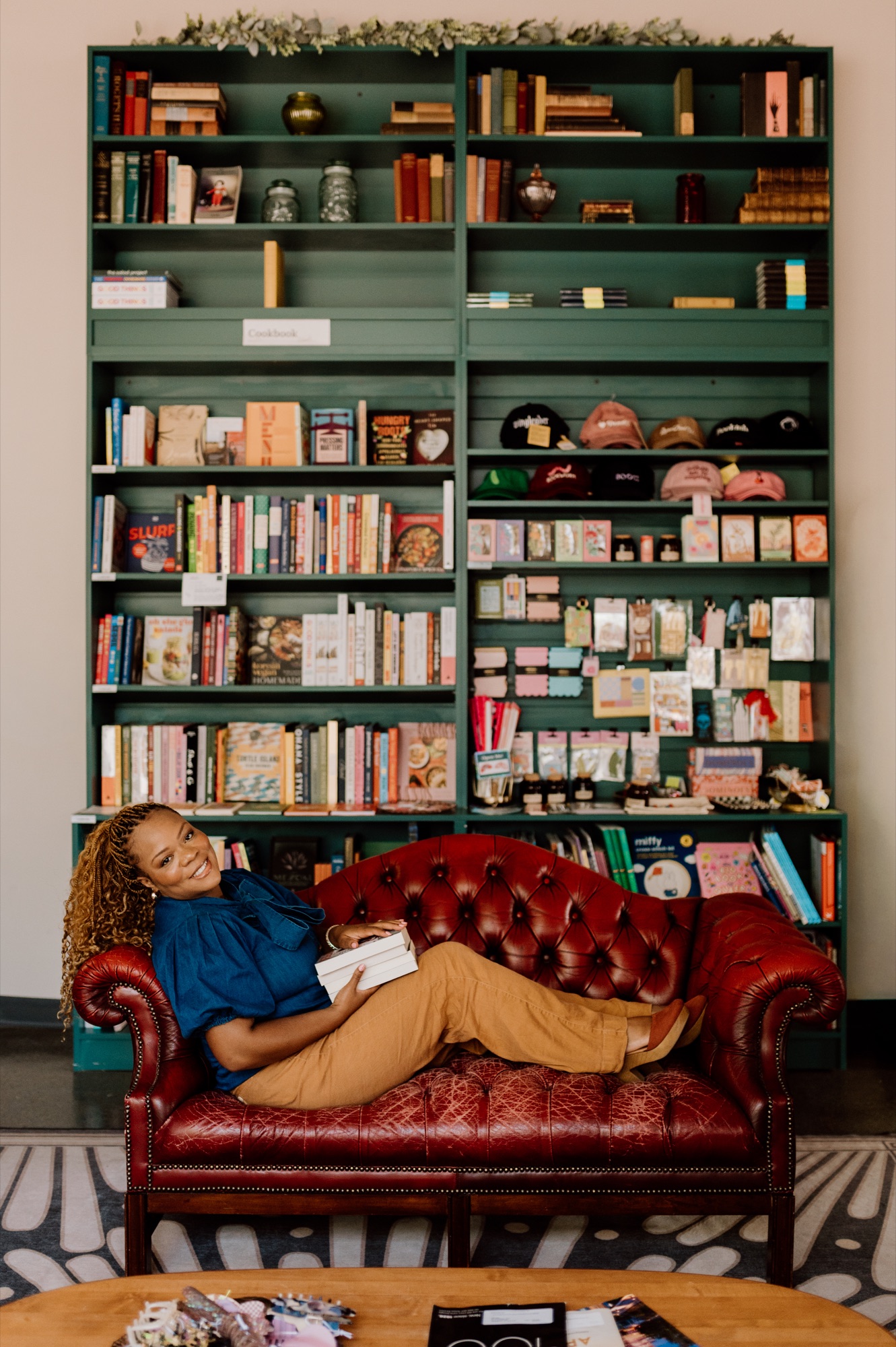 Tam relaxing on a bookstore couch with a stack of books