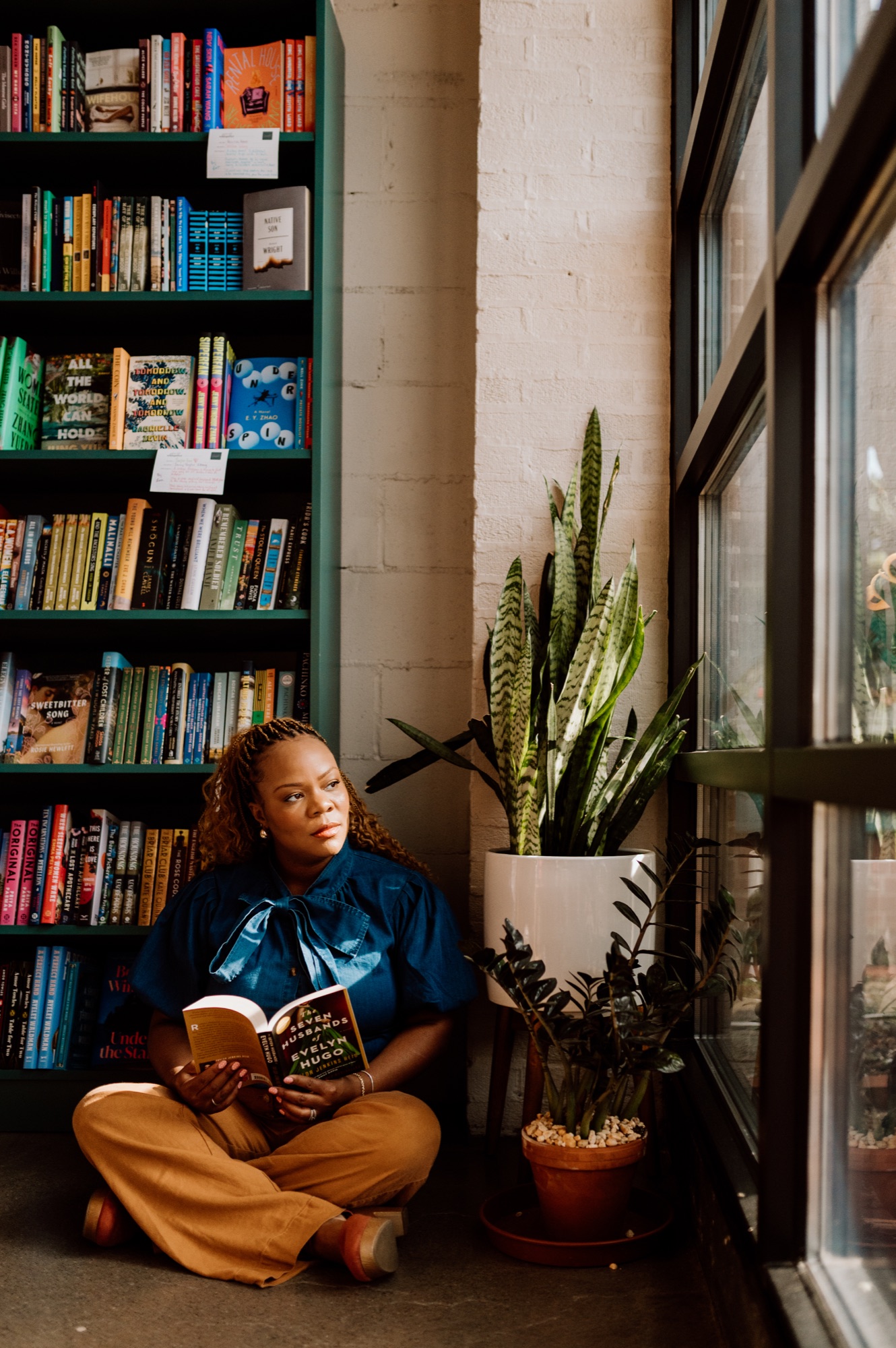 Tam reading a thriller beside a bookstore window